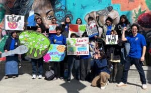 Group of diverse young people holding signs for climate and social justice.